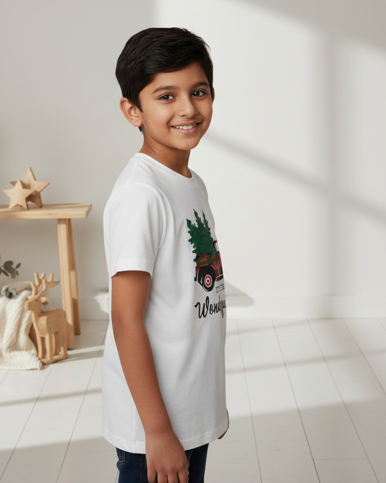Child wearing a white t-shirt with a graphic design in a bright room.