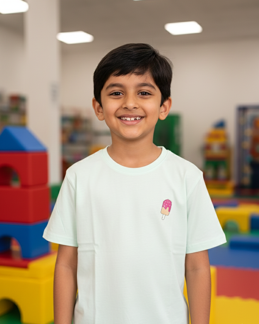 Child wearing a white t-shirt with a small logo in a colorful indoor setting
