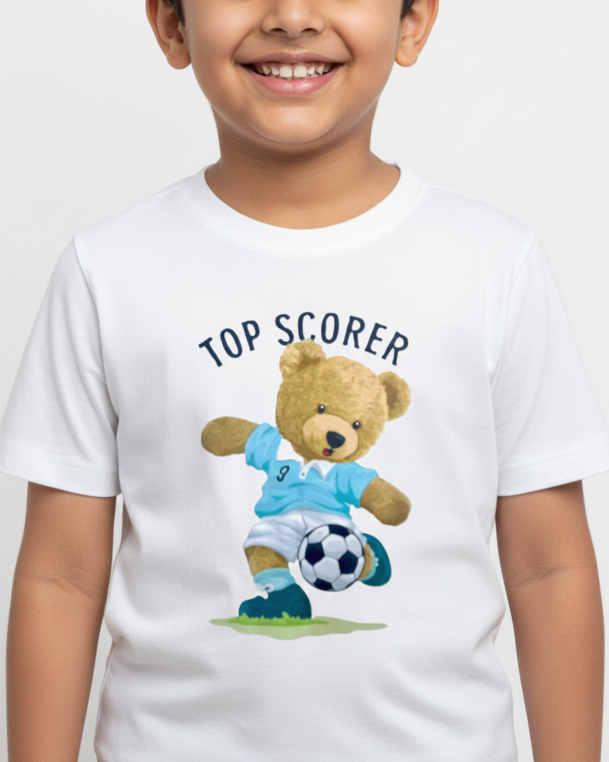 Child wearing a white t-shirt with a teddy bear holding a soccer ball and 'Top Scorer' text.