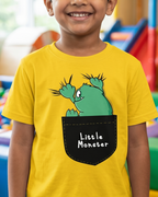 Child wearing a yellow t-shirt with a cartoon design saying little monster in a colorful playroom.