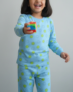 Child wearing blue pajamas with green patterns, holding a colorful toy against a plain background