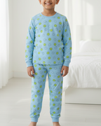 Child wearing blue pajamas with green patterns in a bright room