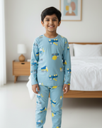 Child wearing blue pajamas with vehicle pattern in a bedroom setting