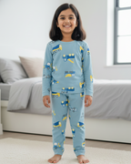 Child wearing blue pajamas with vehicle pattern in a living room.