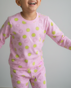Child wearing pink pajamas with green patterns against a plain background