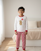Child wearing red and white striped pajama pants and a matching top with a teddy bear design in a bedroom.