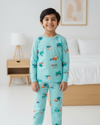 Child wearing teal pajamas with car pattern in a bedroom setting