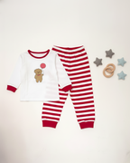 Children's red and white pajama set with teddy bear design on a light gray background.