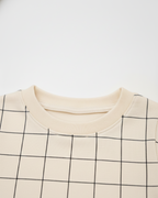 Close-up of a beige sweater with black grid pattern on a white background