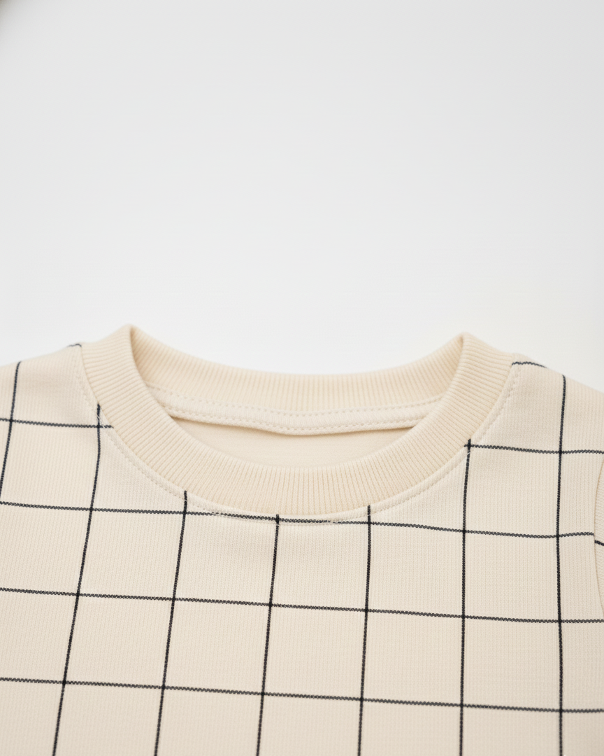 Close-up of a beige sweater with black grid pattern on a white background