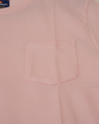 Close-up of a pink shirt with a pocket, brand label visible.