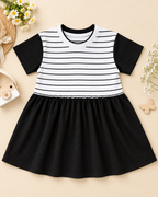 Comfortable kids’ frock featuring a striped bodice, contrast black sleeves, and a soft gathered skirt placed on the light beige background