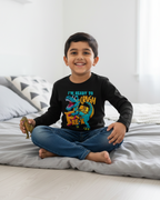Child sitting on a bed wearing a black long-sleeve shirt with colorful graphics and text.