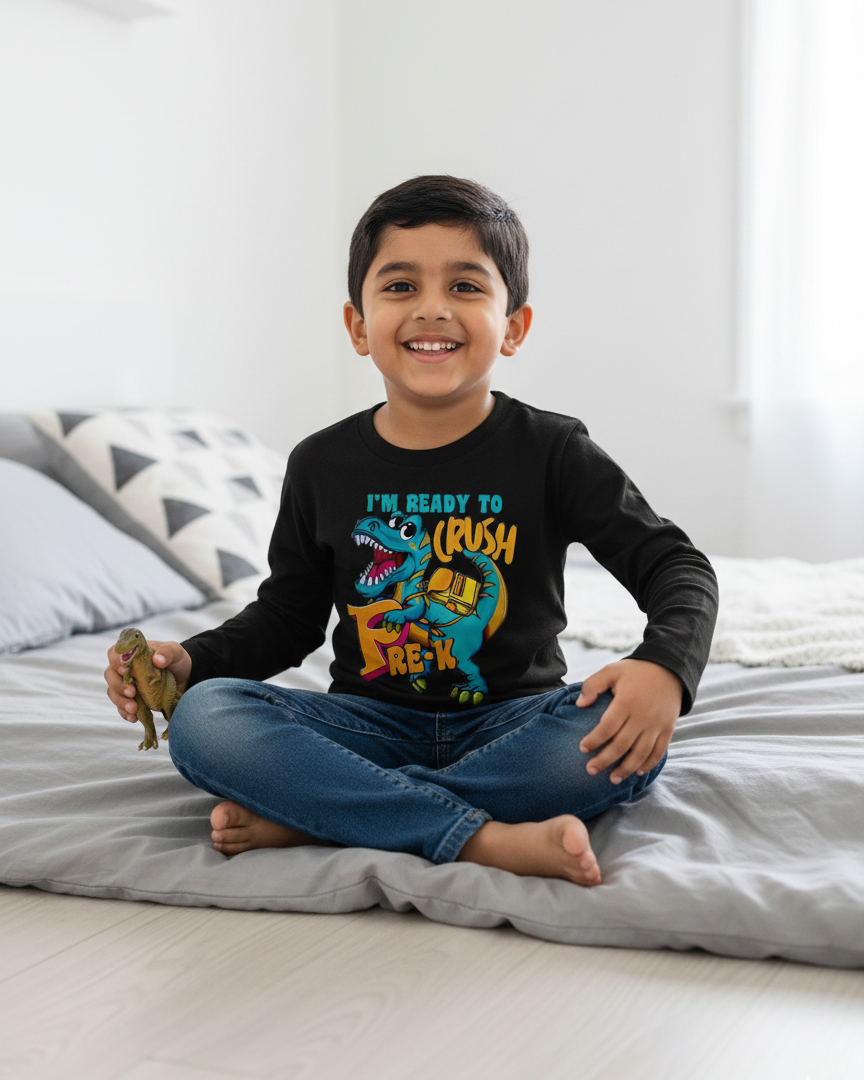 Child sitting on a bed wearing a black long-sleeve shirt with colorful graphics and text.