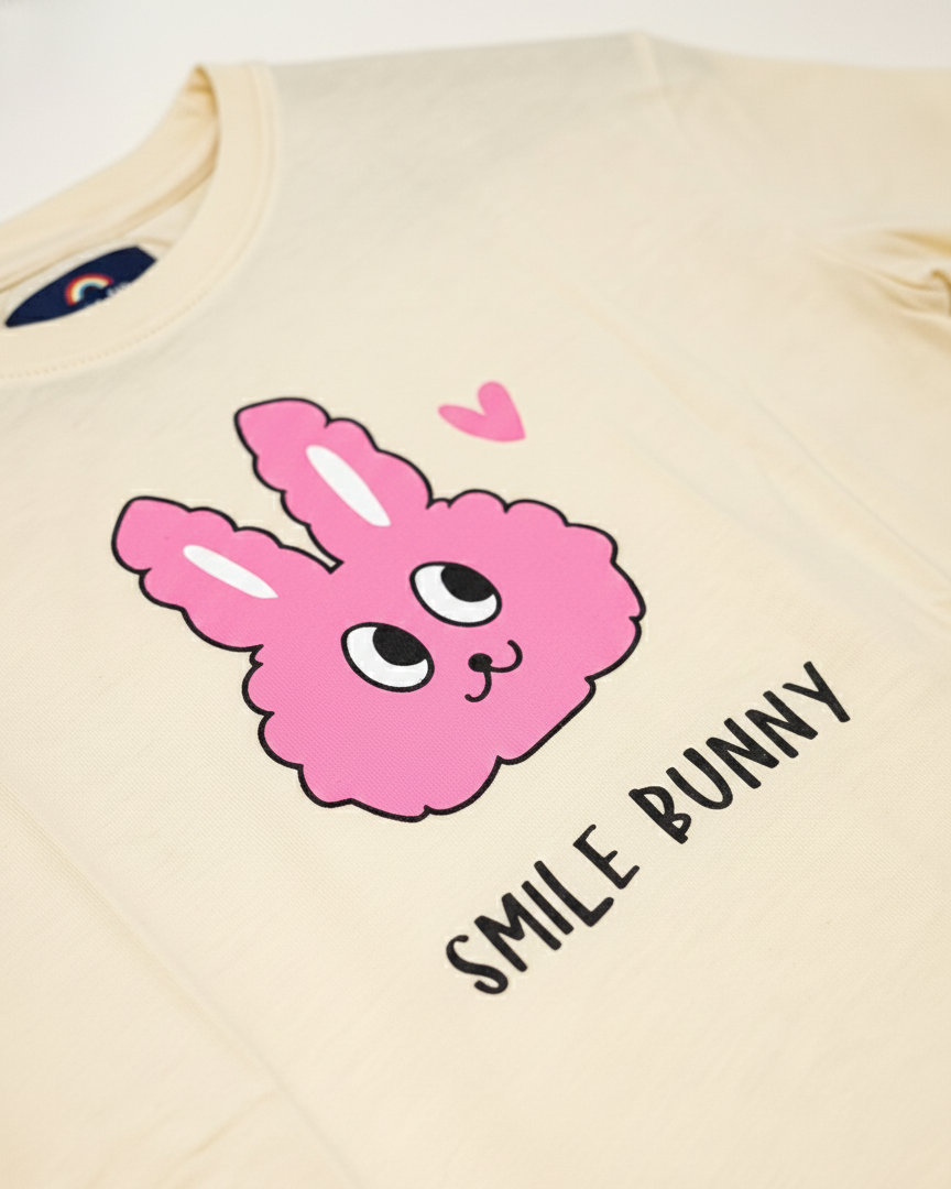 Beige t-shirt with pink 'Smile Bunny' graphic design on a plain background