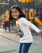 Girl on a swing at a playground wearing a white shirt with a colorful design.