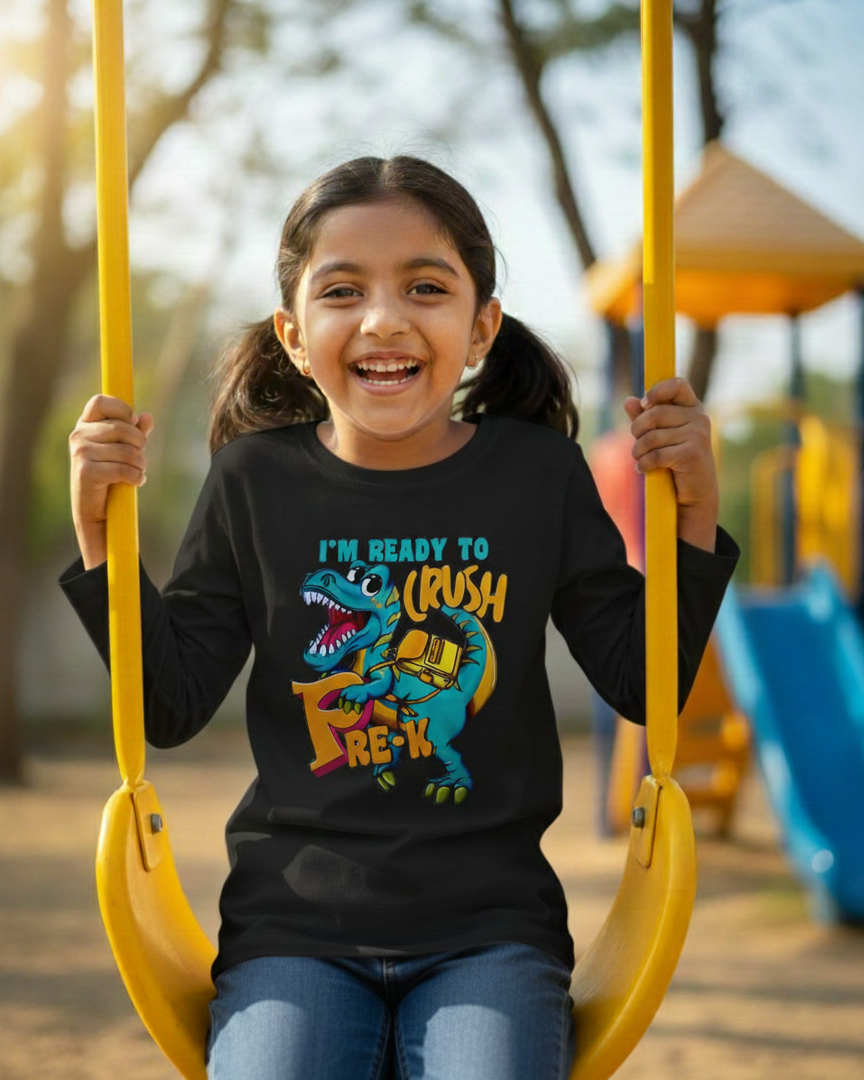Girl on a swing wearing a black t-shirt with a dinosaur graphic and text in a playground setting