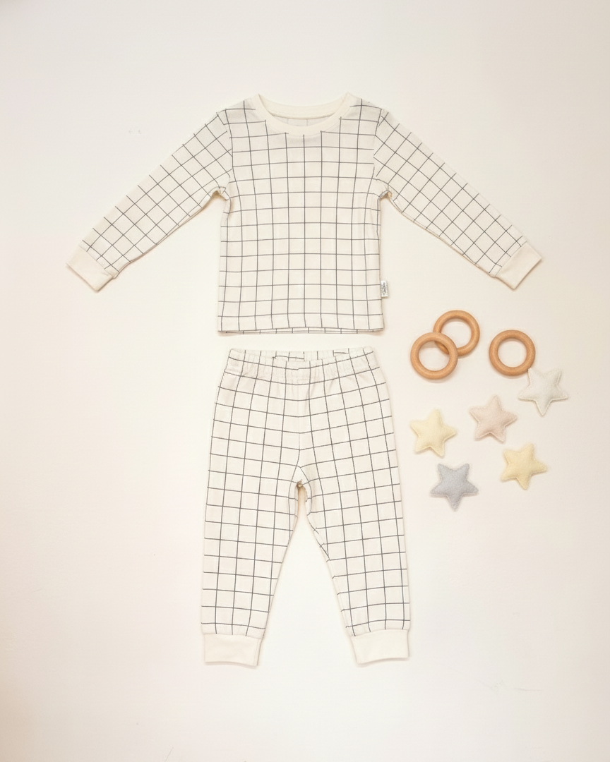 Grid-patterned baby outfit with wooden rings and star-shaped toys on a light background