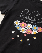 Hello spring print in Black T-shirt placed on the light beige background close view 
