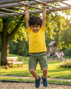Kid with yellow t shirt hanging on the monkey bar