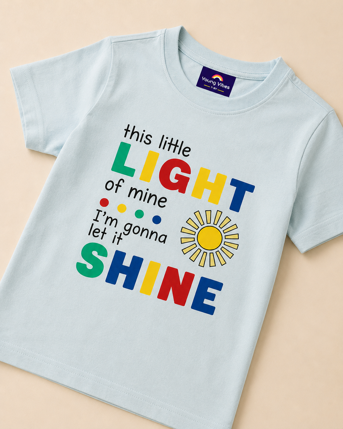 Light blue T-shirt with colourful Little Light print placed on beige background close view