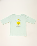 Light blue t-shirt with a sun graphic and text on a light pink background