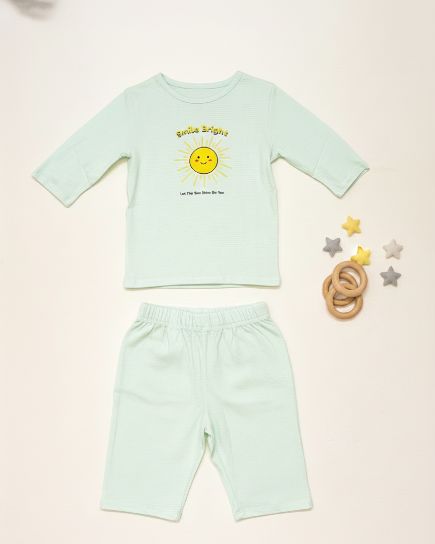 Light green children's outfit with a sun design on a beige background