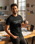 Man holding a mug in an office setting wearing a black t-shirt with text.