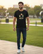 Man walking outdoors in a park wearing a black t-shirt with text and graphics.