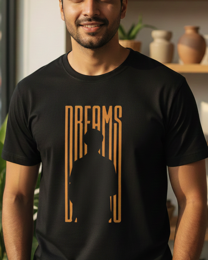 Man wearing a black t-shirt with 'DREAMS' design in a room with plants and shelves