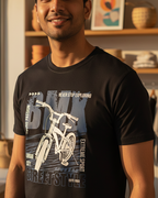 Man wearing a black t-shirt with a bicycle graphic and text indoors.