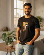 Man wearing a black t-shirt with a graphic design in a bright living room.
