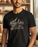 Man wearing a black t-shirt with a mountain design and text in a room with shelves and plants.