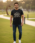 Man wearing a black t-shirt with mountains graphic and text in a park