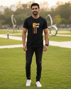 Man wearing a black t-shirt with text on it, standing in a park.