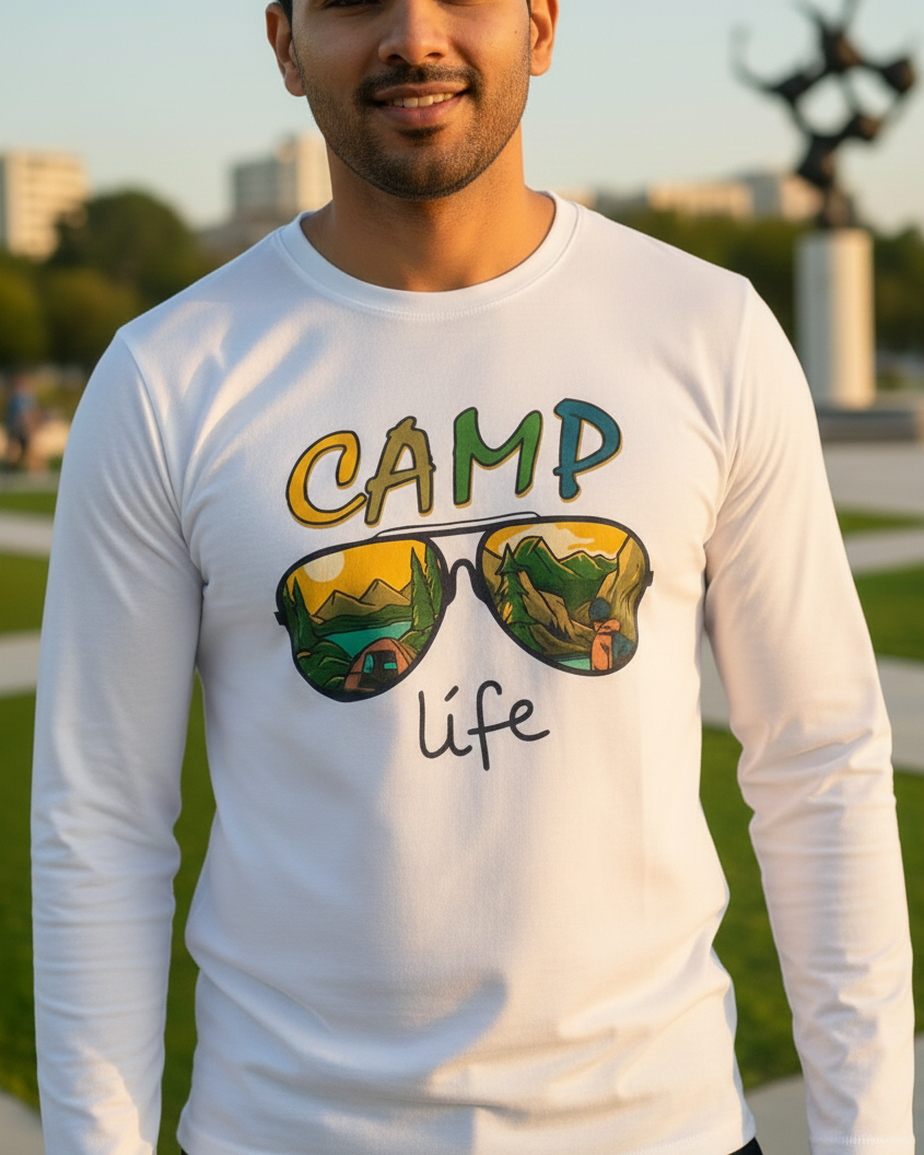 Man wearing a white long-sleeve shirt with 'Camp Life' design outdoors.