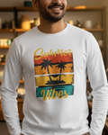 Man wearing a white long-sleeve shirt with 'Summer Vibes' graphic design in a room with shelves and decor.