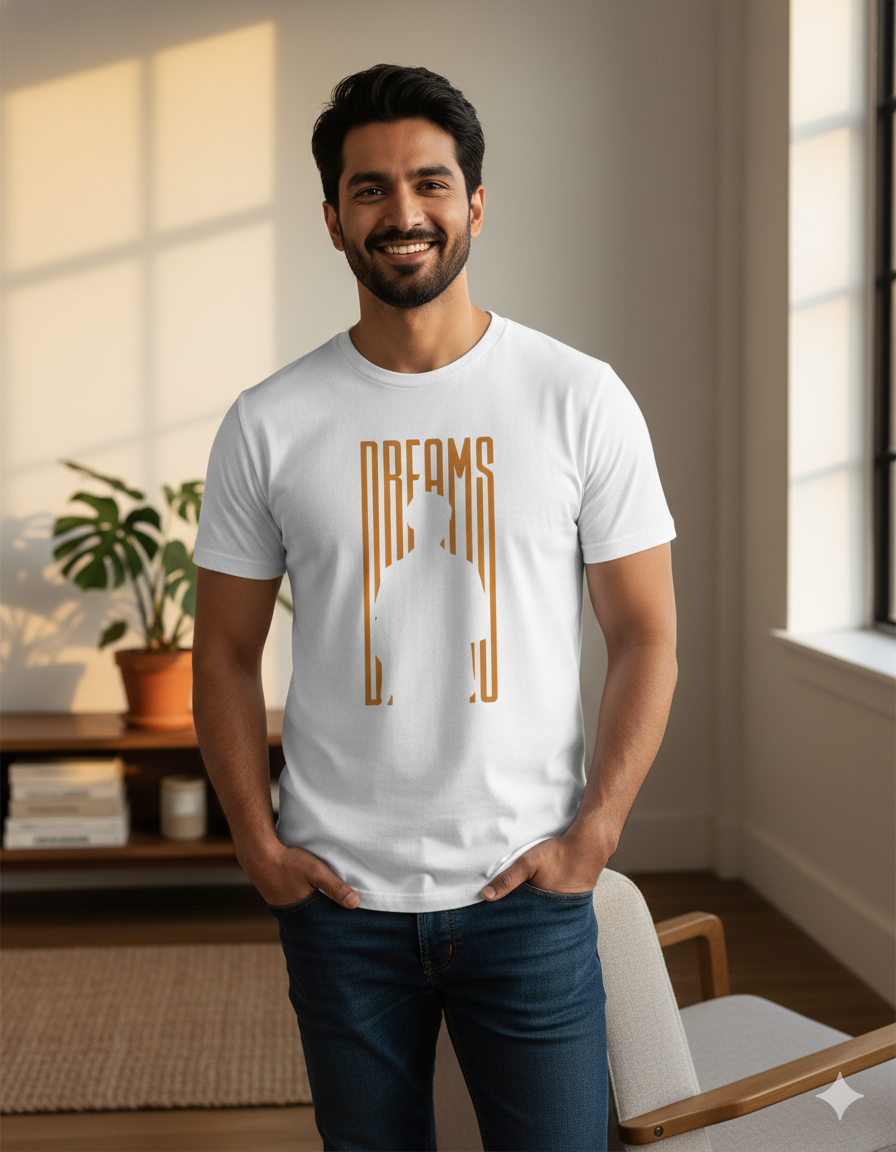 Man wearing a white t-shirt with 'DREAMS' design in a room with natural light