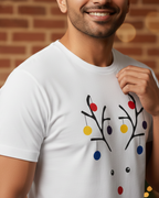 Man wearing a white t-shirt with a colorful reindeer design against a brick wall.