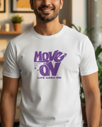 Man wearing a white t-shirt with purple text in a room with plants and decor
