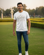 Man wearing a white t-shirt with text and blue jeans standing on grass