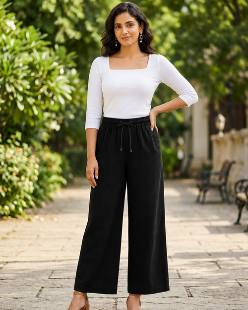 Women in a pathway wearing a white square neck t-shirt and black palazzo pant