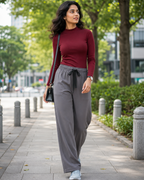 Women walking in a pathway wearing a burgundy mock neck t-shirt and grey palazzo pants