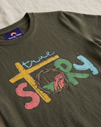 Muddy Green T-shirt with True story colourful print close view placed on the light beige background 