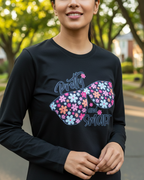 Person wearing a black long-sleeve shirt with a colorful butterfly design and text outdoors.