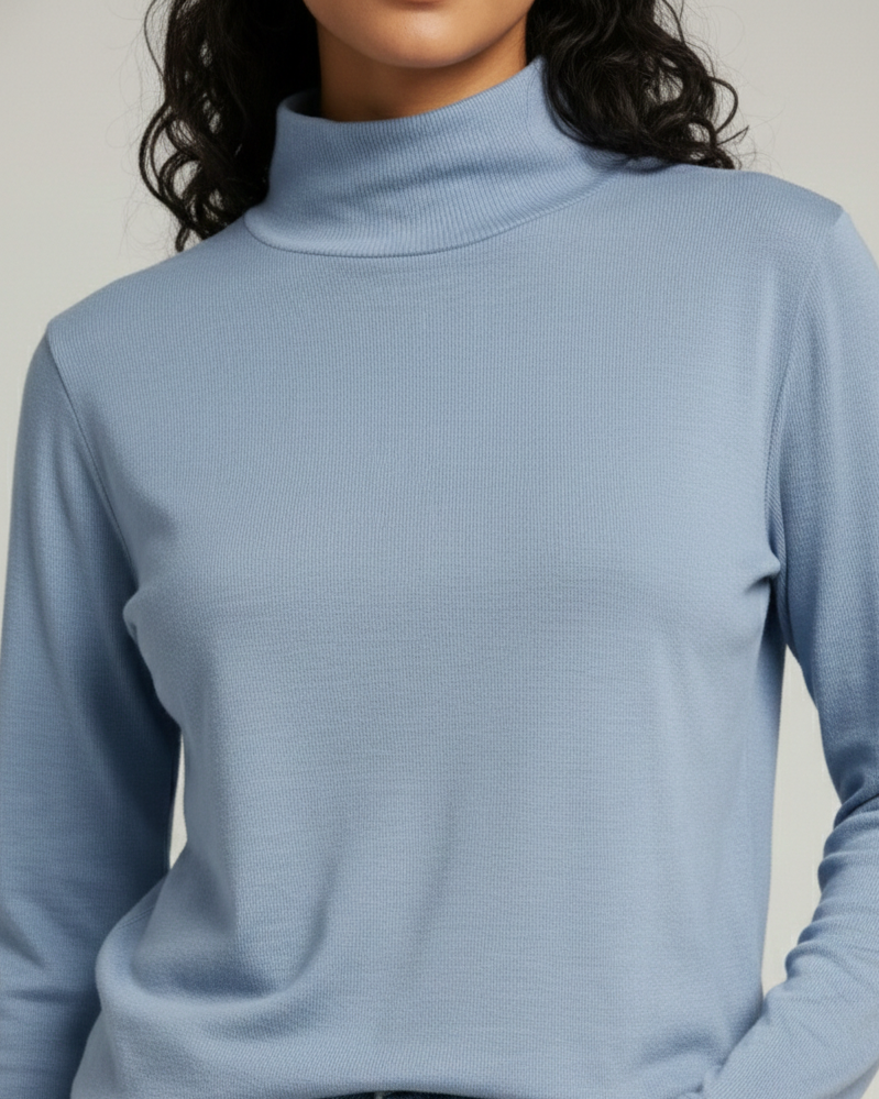 Person wearing a light blue turtleneck sweater with a neutral background