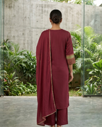 Person wearing a maroon traditional outfit with a garden view in the background