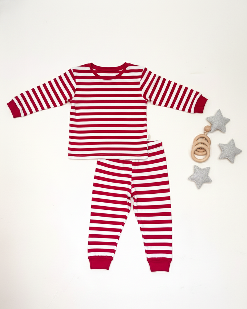 Red and white striped children's pajama set on a white background with wooden toys.