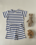 Striped baby romper with a toy rabbit and wooden blocks on a light gray background