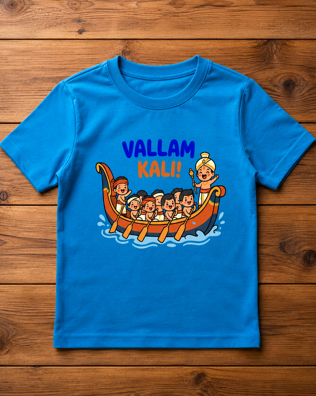 Child wearing a blue t-shirt with 'Vallam Kali!' design in a wooden background